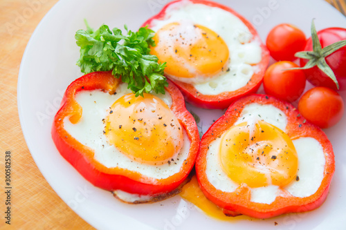 fried eggs in red peppers in a plate close-up. horizontal view from above