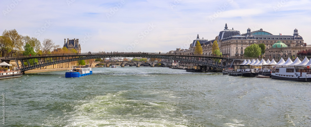 Pedestrian bridge (Passerelle Léopold-Sédar-Senghor) over Seine river, boats and historic buildings of Paris France