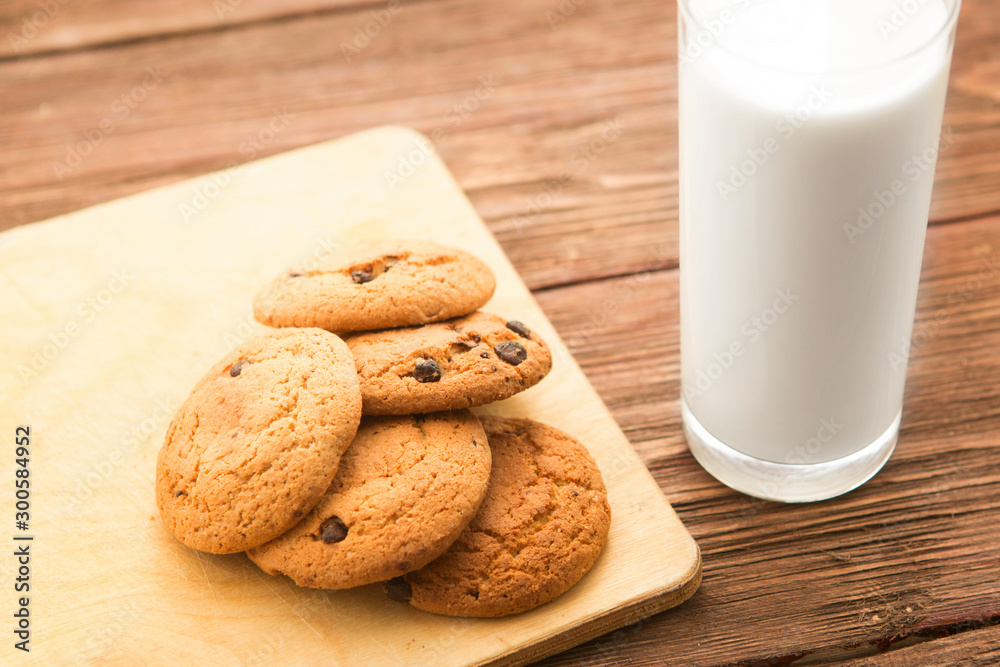 Chocolate chip cookies with milk in glass on rustic wooden table Chocolate chip cookies with milk in glass on rustic wooden table