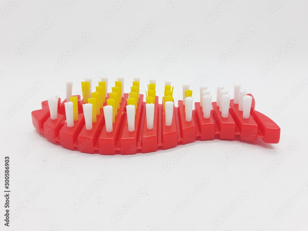 Hand Hold Artistic Red and Yellow Colored Bathroom Toilet Wash Brush with Animal Fish Shape in White Isolated Background