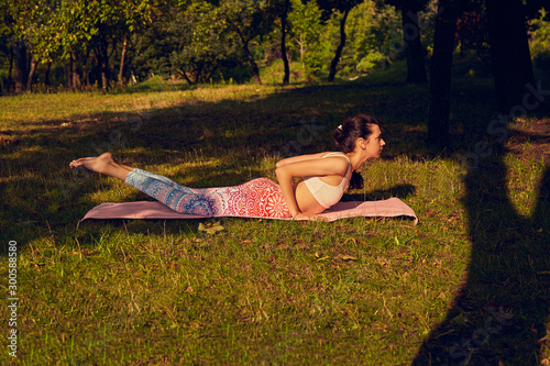 Young girl with assane shalabhasana in a summer park. photo