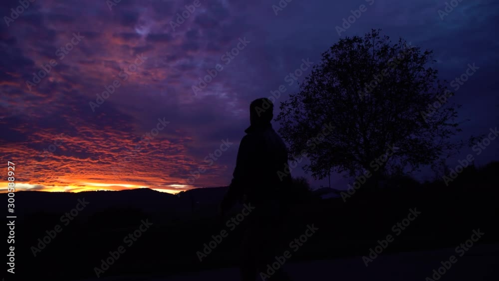 Man walking on the road.A incredible sunset.Flaming sky.Wonderful landscape Man walking on the road.A incredible sunset.Flaming sky.Wonderful landscape