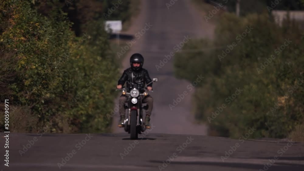 Motorcyclist wearing helmet and black leather jacket, motorcyclist rides with hot asphalt Motorcyclist wearing helmet and black leather jacket, motorcyclist rides with hot asphalt