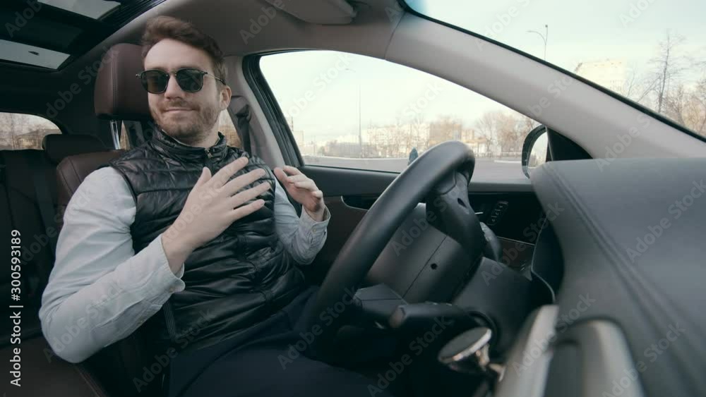 Self-driving autonomous car is parking by itself. A man isn't touching a wheel of an automatic vehicle Self-driving autonomous car is parking by itself. A man isn't touching a wheel of an automatic vehicle