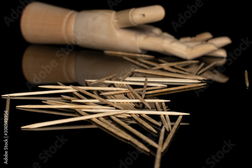 Lot of whole light wooden brown toothpick with wooden hand isolated on black glass photo