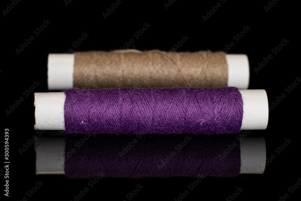 Group of two whole sewing thread spool isolated on black glass Group of two whole sewing thread spool isolated on black glass
