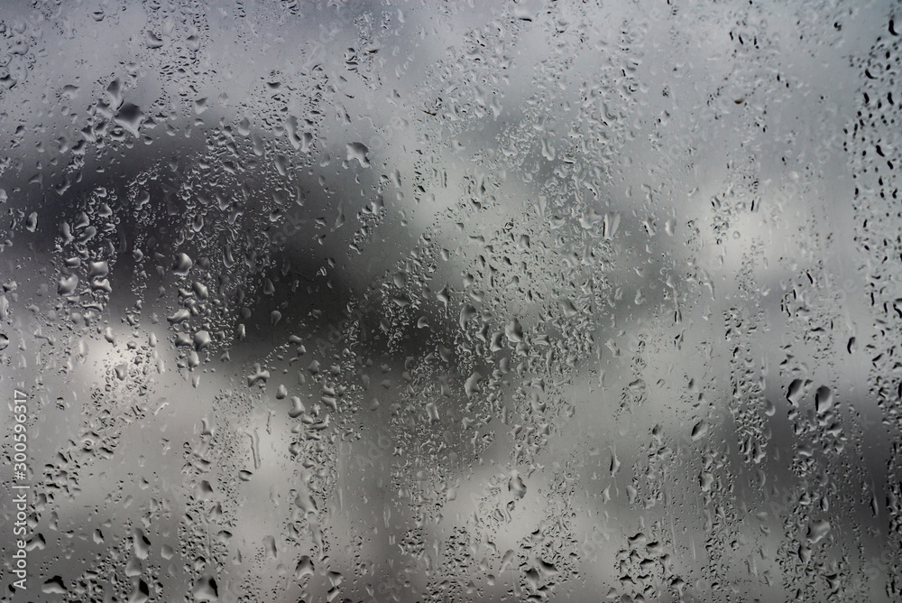 Rain drops on a window against cloudy sky. city in rainy season