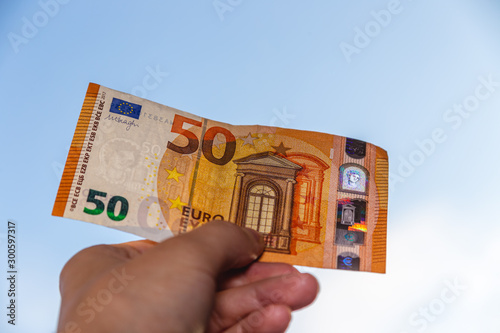 hand holding 50 euro banknote over clear blue sky, Exchange money. Financial concepts , Business Concept.