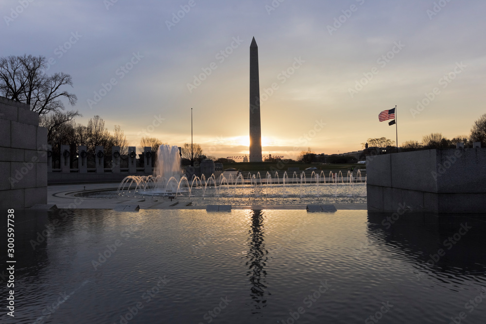 Beautiful sunrise behind America's national monument, the Washington Monument with National WWII Memorial & Rainbow Pool in the foreground