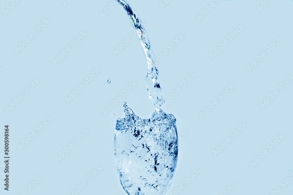Pour water onto a glass of water with splash isolated on white background Pour water onto a glass of water with splash isolated on white background
