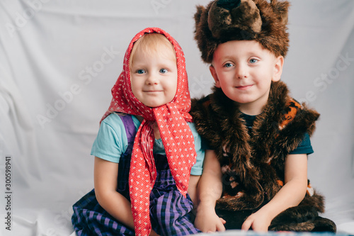 Beautiful couple of lovely children in bear costume and russian cartoon clothes sitting on bed with funny faces. Soft focus portrait of little children in costumes