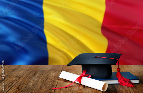 Romania education concept. Graduation cap and diploma on wooden table, national flag background. Succesful student.