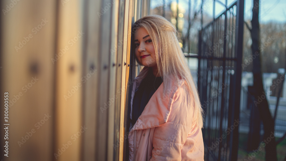 A portrait of a beautiful girl, posing near a wooden fence at sunset in springtime. A portrait of a beautiful girl, posing near a wooden fence at sunset in springtime.