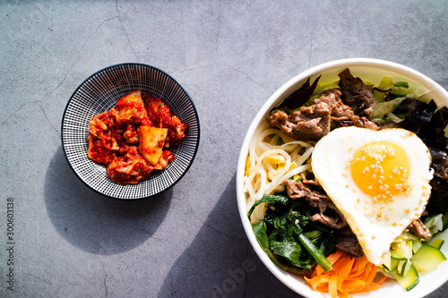 Traditional Korean dishes. Bi bim bap and kimchi on concrete background. Top view.