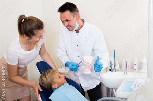 Professional in uniform is telling to young boy and mother about hygiene