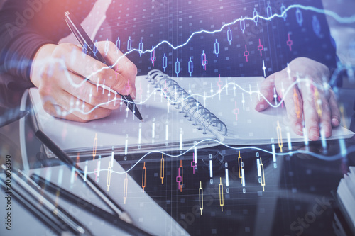 Forex chart hologram on hand taking notes background. Concept of analysis. Multi exposure © peshkova