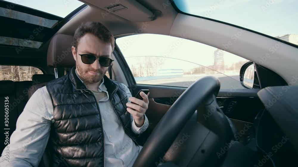 Male driver with a smartphone is sitting in an automatic car Male driver with a smartphone is sitting in an automatic car