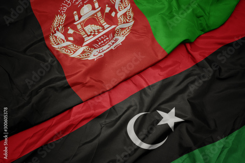 waving colorful flag of libya and national flag of afghanistan.