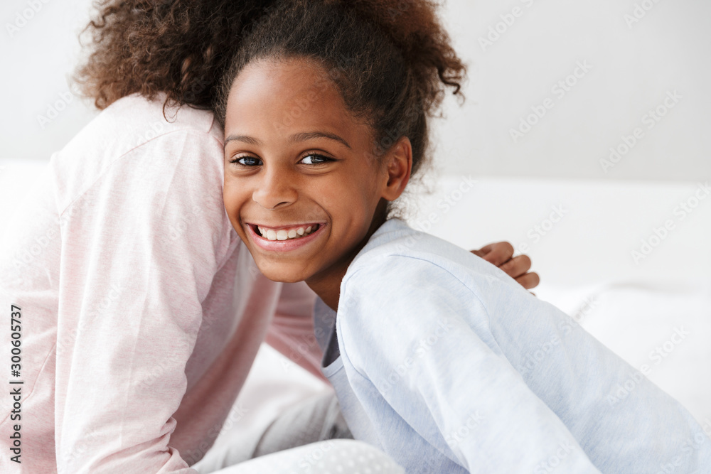Image of african american woman and her little daughter sitting on sofa Image of african american woman and her little daughter sitting on sofa