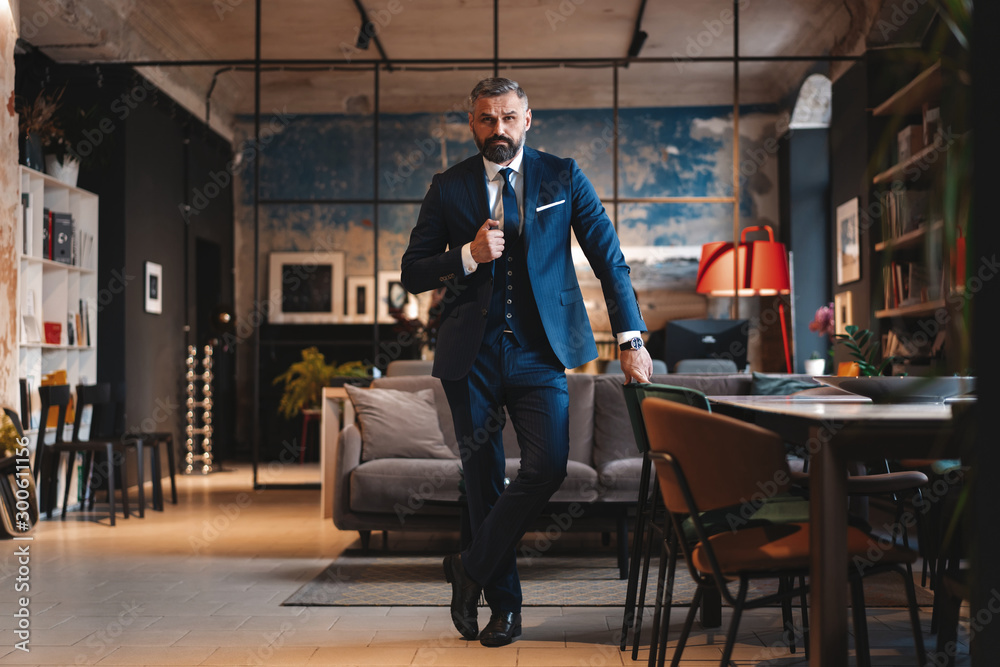 Stylish bearded man in a suit standing in modern office