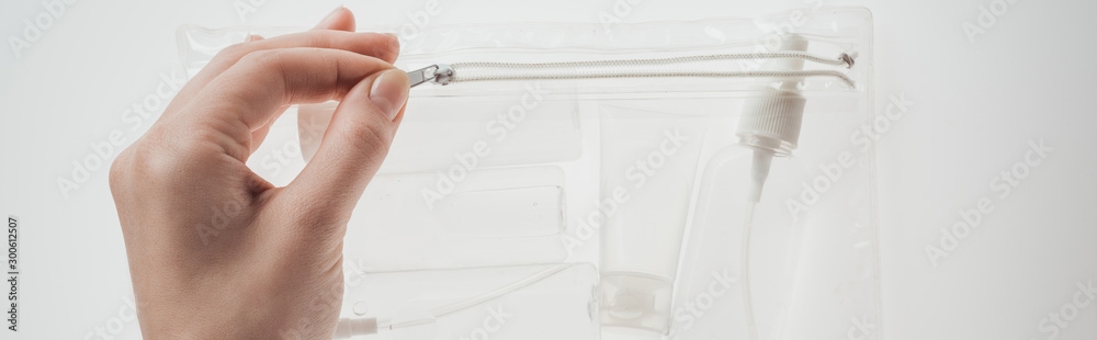 Fototapeta premium panoramic shot of woman holding cosmetic bag with bottles and tube on white background