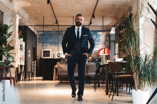 Stylish bearded man in a suit standing in modern office