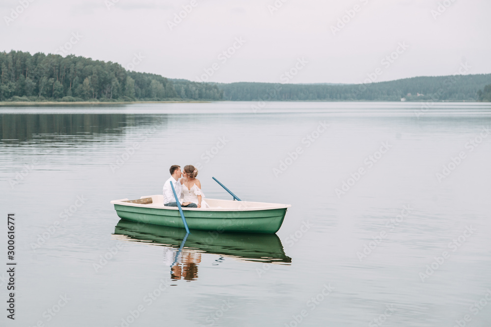  Stylish wedding in European style. Happy couple on a boat on the lake.