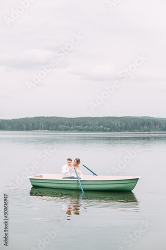  Stylish wedding in European style. Happy couple on a boat on the lake. © pavelvozmischev