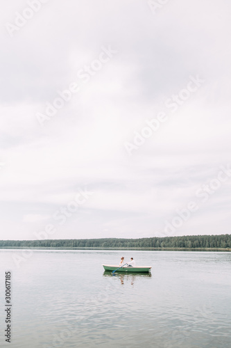  Stylish wedding in European style. Happy couple on a boat on the lake.