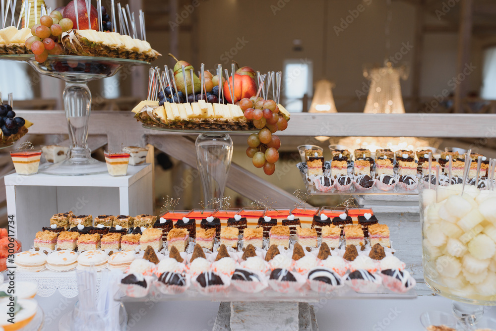 Fototapeta premium desserts with fruits, mousse, biscuits. Different types of sweet pastries, small colorful sweet cakes, macaron, and other desserts in the sweet buffet