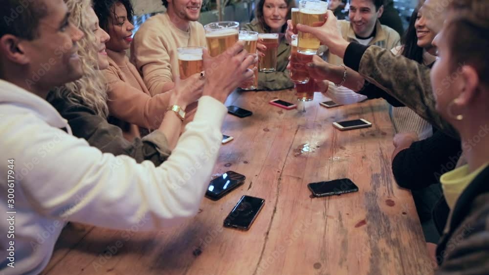 Group of friends enjoying a beer at pub in London, toasting and laughing