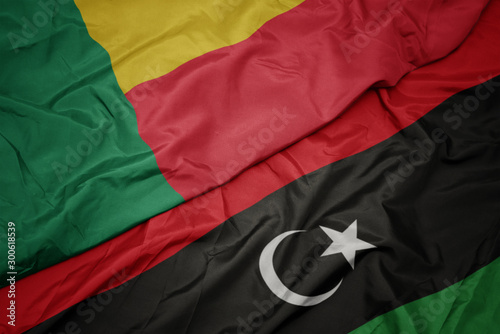waving colorful flag of libya and national flag of benin.