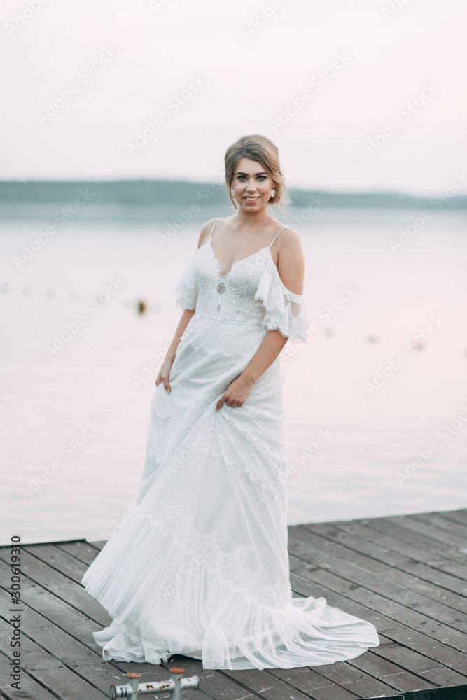 Wedding dress in European style. Happy bride at sunset on the lake. Wedding dress in European style. Happy bride at sunset on the lake.