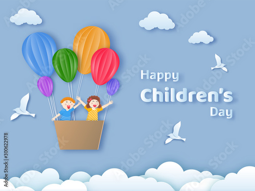 Happy Children's Day text with happy kids flying from hot air balloons on cloudy background in paper cut style. Can be used as greeting card or poster design.