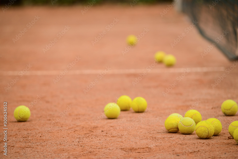 Plenty of tennis yellow balls on the ground of outdoor court.