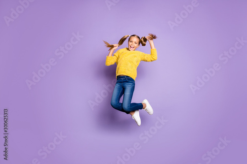 Full size photo of cheerful candid kid jump hold pigtails enjoy autumn holidays wear casual style clothes isolated over purple color background