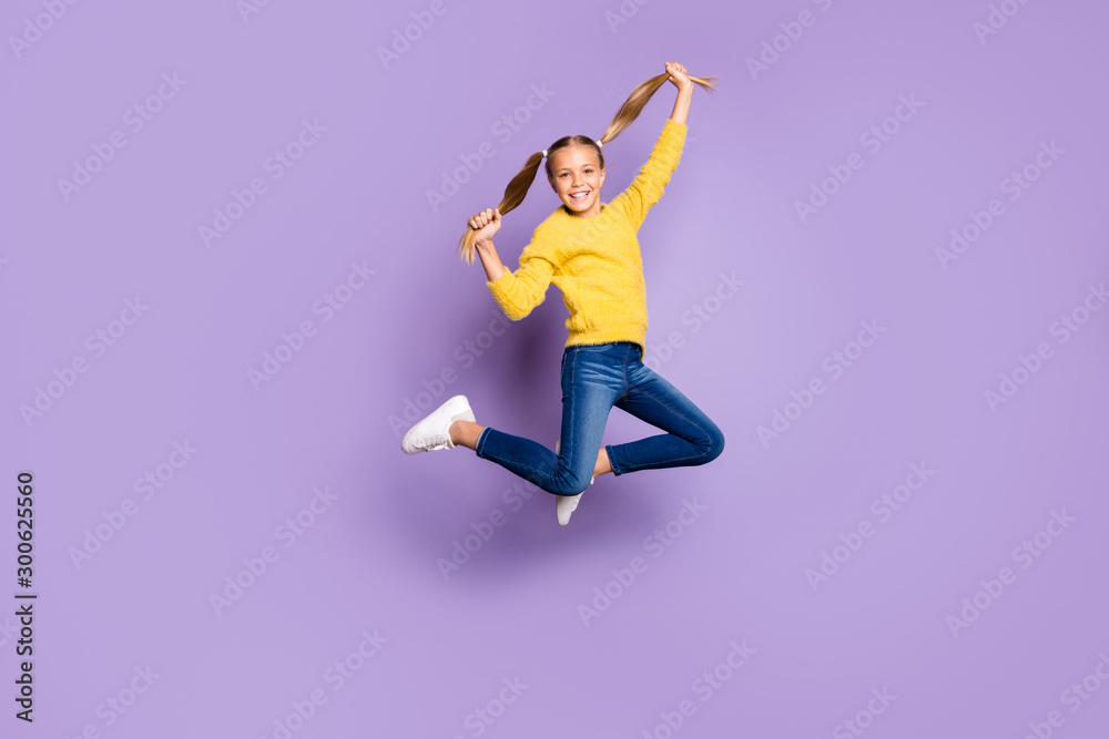 Full body photo of cheerful cute kid have fun on spring holidays jump hold pigtails wear casual style clothing sneakers isolated over violet color background