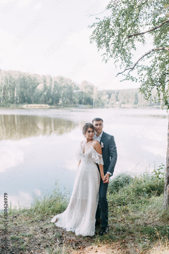 Stylish European wedding at sunset. Happy couple in the forest on the lake.