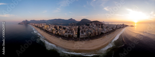 Empty Ipanema and Leblon beach at sunrise with the iconic Rio de Janeiro skyline in the background with the Two Brothers, Corcovado and Sugarloaf mountain and sun just above Arpoador rock photo