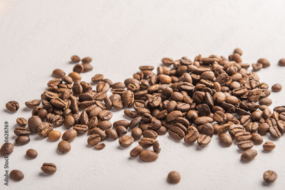 Coffee beans close up scattered on a light background Coffee beans close up scattered on a light background