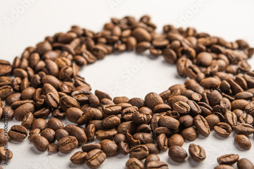 Coffee beans close-up scattered on a light background. Centered space for text
