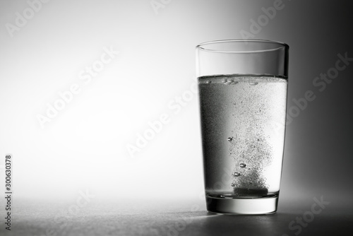 Effervescent aspirin tablet dropping to glass of water