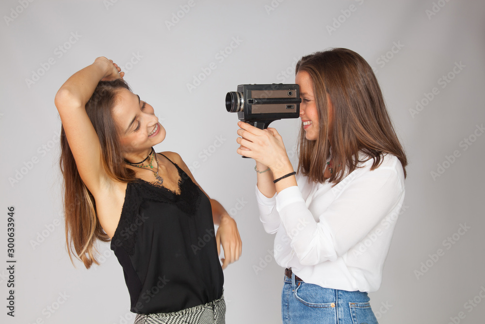 Dos chicas jugando con una cámara de cine antigua de película de 8 mm; chicas haciendo de artistas de actriz y de directora de cine. Dos chicas jugando con una cámara de cine antigua de película de 8 mm; chicas haciendo de artistas de actriz y de directora de cine.