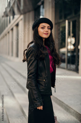 young woman wearing black hat is walking in the streets of City © producer