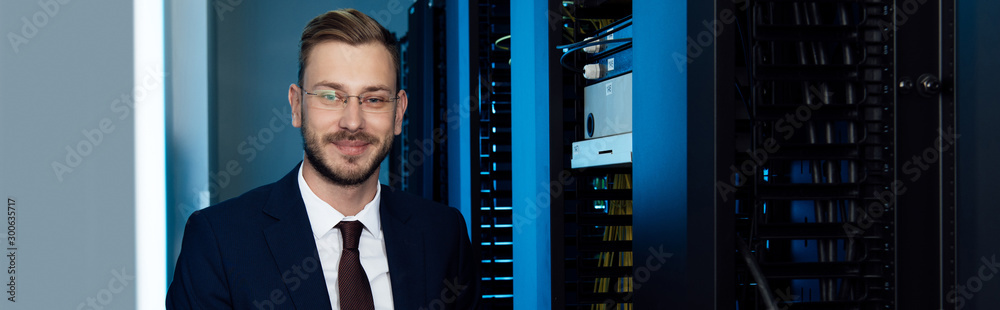 panoramic shot of businessman in glasses smiling in data center panoramic shot of businessman in glasses smiling in data center