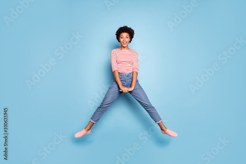 Full size photo of cheerful afro american girl jump have rest relax spring journey wear casual style outfit isolated over blue color background