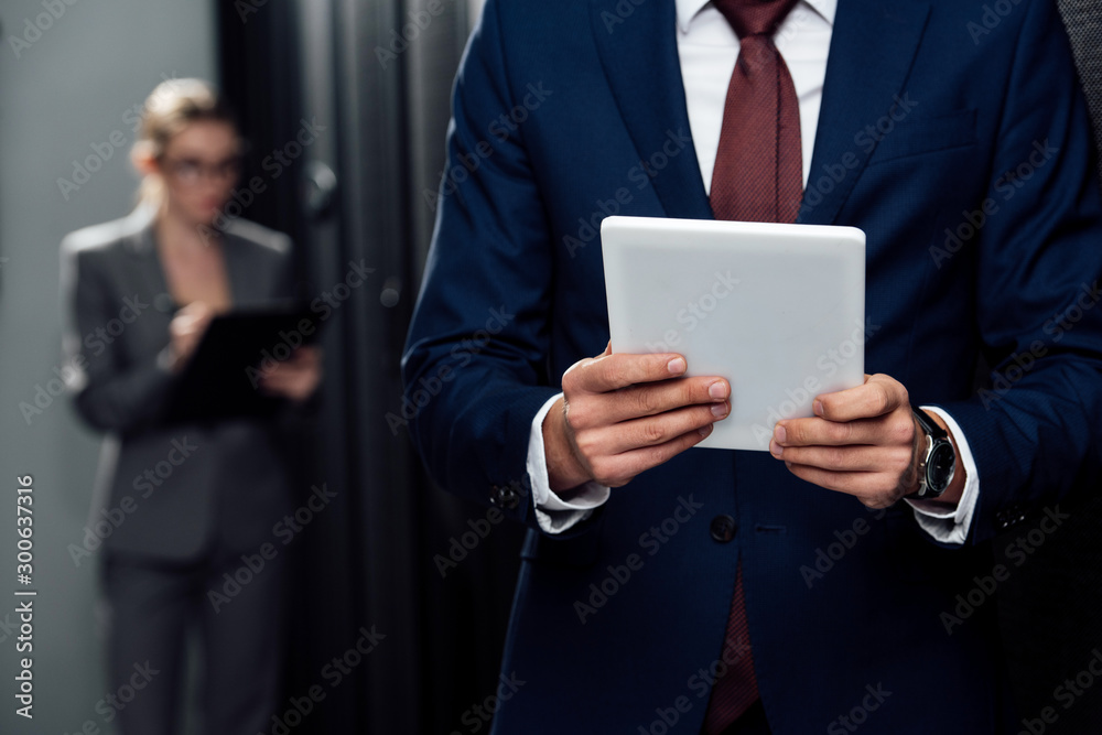 cropped view of businessman holding digital tablet near businesswoman and server racks cropped view of businessman holding digital tablet near businesswoman and server racks