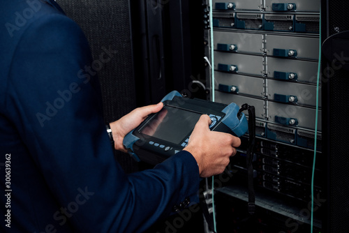 cropped view of man holding reflectometer in server room photo