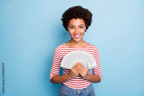 Photo of cheerful curly wavy nice pretty positive girlfriend holding fan of money with toothy smile proud of her success in jeans denim isolated pastel blue color background