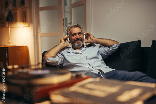 mid aged man relaxing in his home listening to a music photo